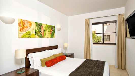 Ett sovrum med en dubbelsäng och väggdekorationer som föreställer blommotiv. (AI-genererad text)