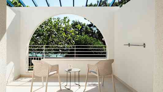 Utsikt från en terrass med två stolar och ett bord, mot vegetationen utanför. (AI-genererad text)