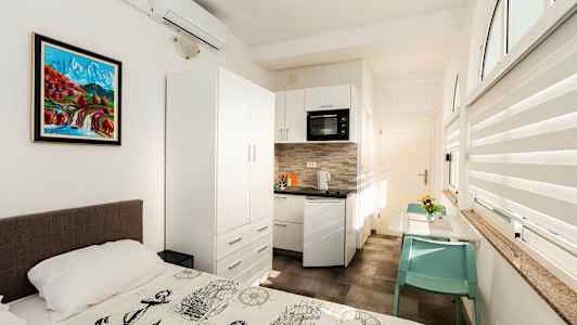 Ett ljust rum med en säng framför ett pentry och ett matbord. (AI-genererad text)