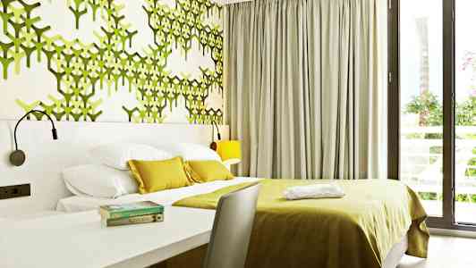 Modernt hotellrum med grönt dekorerad vägg och stora fönster. (AI-genererad text)