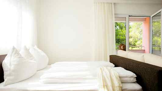 Ett ljust rum med en säng nära fönster och balkong. (AI-genererad text)