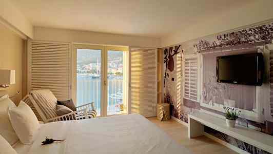 Sovrum med utsikt över havet genom glasdörrar, en säng och en vägg med dekorativ fotografering. (AI-genererad text)