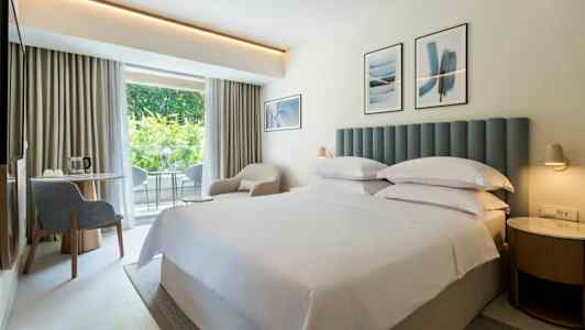 Hotellrum med dubbelsäng och inredning i ljusa färger. (AI-genererad text)