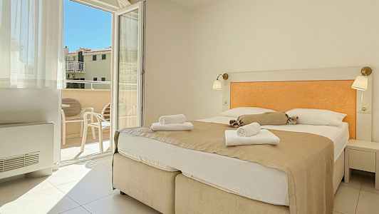 Rum med dubbelsäng och utsikt mot balkong. (AI-genererad text)