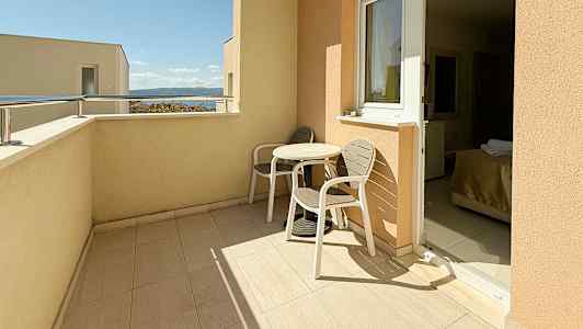 En balkong med två stolar och ett bord, med en utsikt mot himlen och havet. (AI-genererad text)