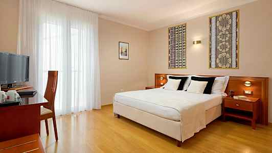 Ett hotellrum med en dubbelsäng, ett skrivbord och en stol samt en TV. (AI-genererad text)