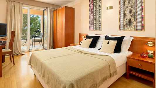 Dubbelrum med dubbelsäng, utsikt mot balkong med sittmöbler. (AI-genererad text)