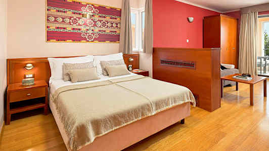 Hotellrum med en dubbelsäng, nattduksbord och konst på väggen. (AI-genererad text)