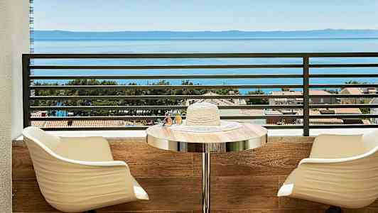 Utsikt över havet från en balkong med sittplatser och ett bord. (AI-genererad text)