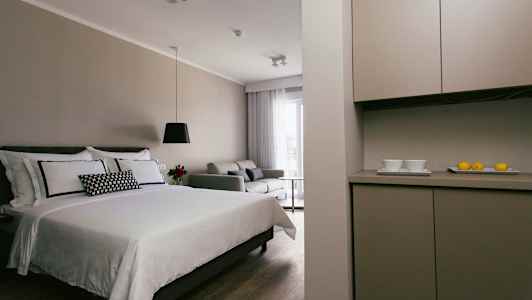 Modernt hotellrum med en säng, soffa och köksområde. (AI-genererad text)