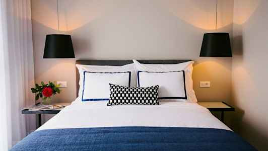 Bild på en bäddad säng med dekorativa kuddar och hängande lampor. (AI-genererad text)