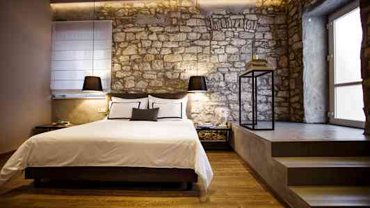 Ett stilfullt sovrum med en säng och stenmur. (AI-genererad text)