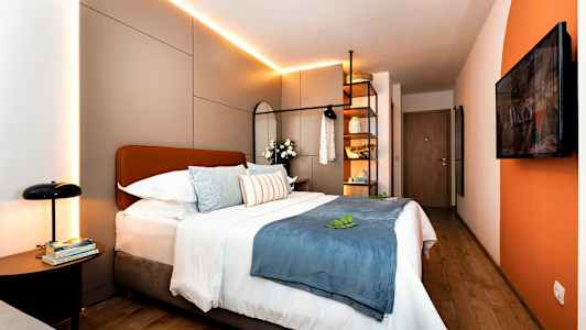 Modernt hotellrum med dubbelsäng, dekorativa kuddar och belysning. (AI-genererad text)