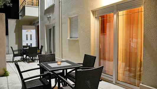 Utemöbler framför en byggnad med fönster och dörr. (AI-genererad text)