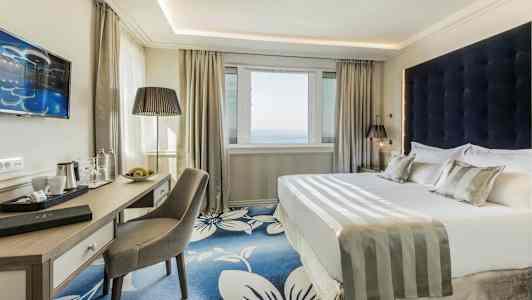 Ett modernt hotellrum med en dubbelsäng och skrivbord. (AI-genererad text)