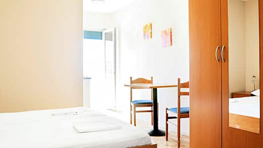 Ett hotellrum med två enkelsängar, ett bord med två stolar och en garderob. (AI-genererad text)