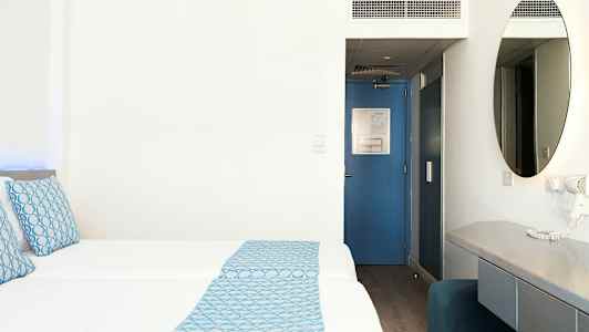 Hotellrum med två bäddar, blå detaljer och skrivbord. (AI-genererad text)