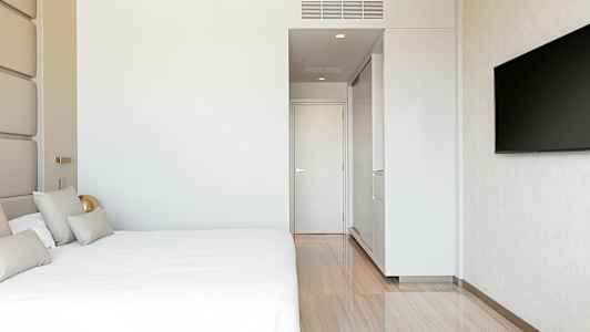 Ett modernt hotellrum med en stor säng, vit vägg, en dörr och en väggmonterad TV. (AI-genererad text)