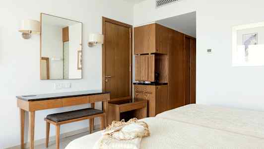 Ett hotellrum med en spegel, träbord, hyllor och en säng. (AI-genererad text)