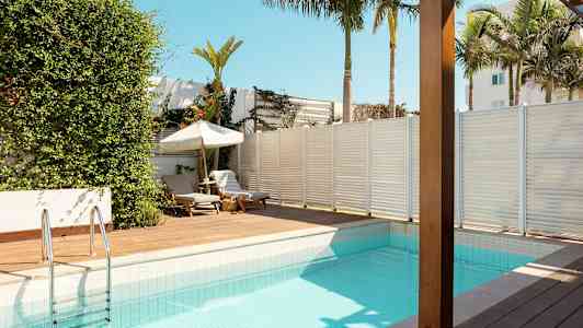 En swimmingpool med soldäck och solstolar i tropisk miljö. (AI-genererad text)