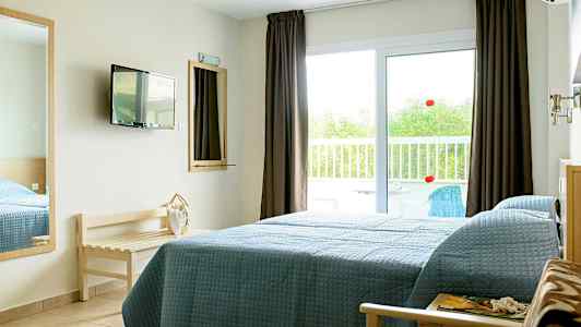 Ett hotellrum med en säng bredvid en glasdörr som leder till en balkong. (AI-genererad text)