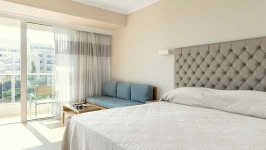 Ett hotellrum med en säng, en blå soffa och en balkong. (AI-genererad text)