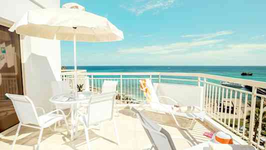 En solig terrass med utsikt över havet, stolar och parasoll. (AI-genererad text)