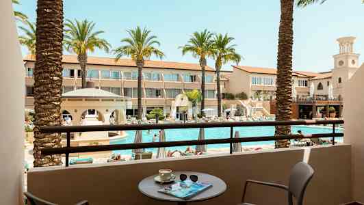 Vy från en balkong över en pool och omgivande hotellbyggnader. (AI-genererad text)