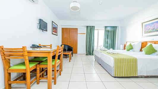 Ett hotellrum med en säng, ett matbord med stolar och en väggmonterad TV. (AI-genererad text)