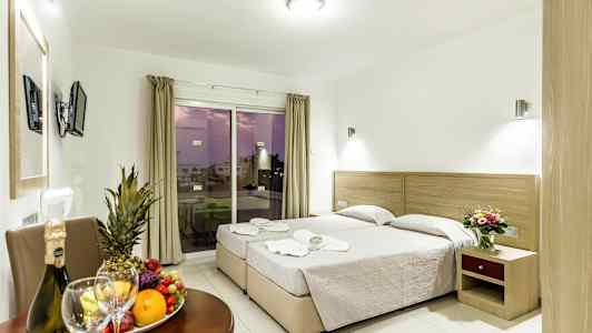 Bild av ett hotellrum med två enkelsängar, ett bord med frukt och dryck samt en balkong med utsikt. (AI-genererad text)