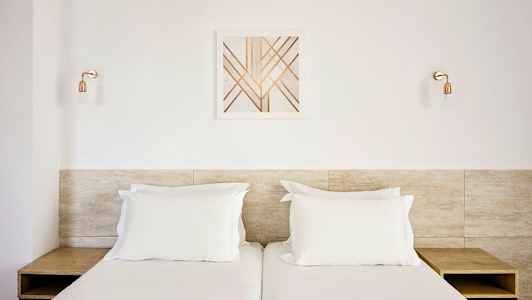 Två enkelsängar med vita sängkläder, ett huvudgavel av trä, och en modern väggdekor ovanför. (AI-genererad text)