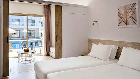 Hotellrum med två enkelsängar och utsikt mot en utomhuspool och solstolar. (AI-genererad text)