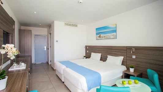 Hotellrum med två sängar, ett bord och stolar. (AI-genererad text)