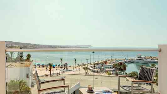 Utsikt från en hotellbalkong över en marina och havet. (AI-genererad text)