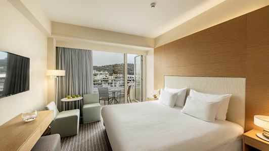 Hotellrum med dubbelsäng, sittplats och balkong med utsikt. (AI-genererad text)