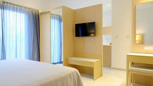 Hotellrum med säng, TV på väggen och spegel vid ett skrivbord. (AI-genererad text)