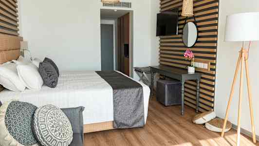 Ett stilfullt hotellrum med en säng, dekorativa kuddar och ett skrivbord. (AI-genererad text)