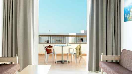 Ett hotellrum med utsikt över en balkong med ett bord och stolar. (AI-genererad text)