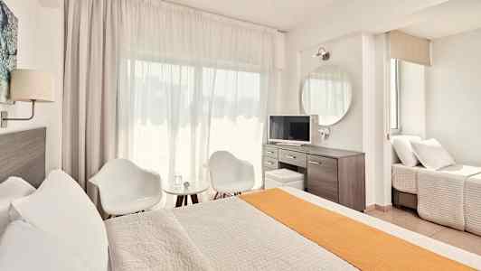 Ett ljust och modernt hotellrum med säng, sittgrupp och skrivbord. (AI-genererad text)