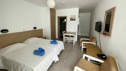 Hotellrum med två enkelsängar, bord med stolar och en soffgrupp. (AI-genererad text)