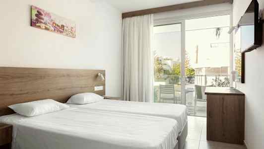 Dubbelrum med två enkelsängar, en glasdörr till balkongen och en vägg-TV. (AI-genererad text)