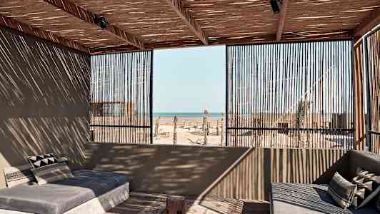 En öppen uteplats med soffor där taket och väggarna är av trä med havsutsikt. (AI-genererad text)