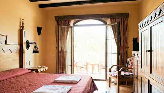 Ett hotellrum med dubbelsäng, handdukar, träinredning och en balkong med utsikt. (AI-genererad text)