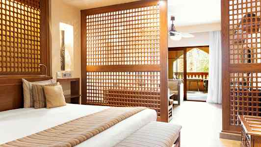 Välmöblerat sovrum med dekorativa träpaneler som avgränsar till ett vardagsrum. (AI-genererad text)