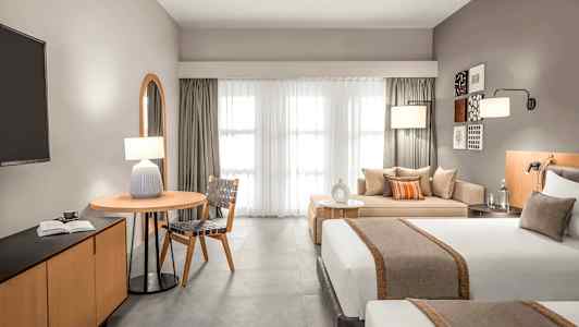 Modern hotellrum med två sängar, sittgrupp och ett bord. (AI-genererad text)