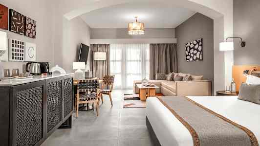 Ett hotellrum med en säng, sittgrupp och matbord, samt modern inredning. (AI-genererad text)