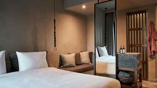 Ett sovrum med en stor säng, kuddar, en soffa och ett högt spegel. (AI-genererad text)