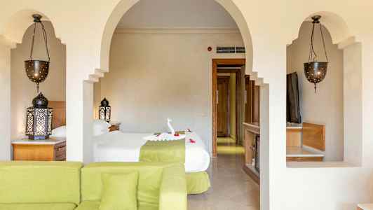 Vardagsrum med grön soffa, sovrum med två enkelsängar, orientaliska lampor och upplysta detaljer. (AI-genererad text)