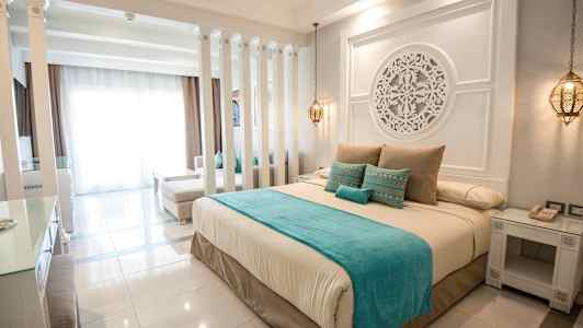 En elegant hotellrum inrett med en stor säng, dekorativa detaljer och mjuka färger. (AI-genererad text)