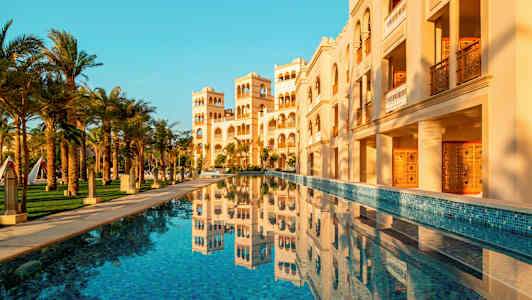 En byggnad med arkitektoniska detaljer och en pool i förgrunden. (AI-genererad text)